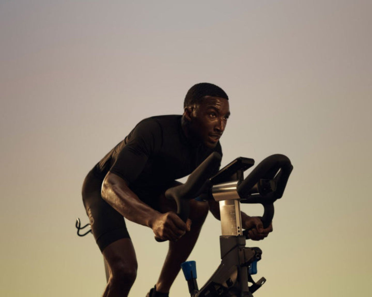 Man exercising on a stationary bike against a gradient background