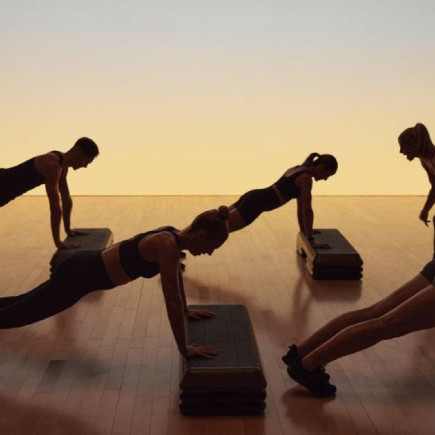 Group of people doing push-ups on a wooden floor with a warm glow
